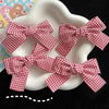 Several red and white plaid fabric bows are displayed on a white plate.