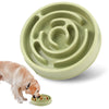A light green anti-gulping slow feeder bowl for dogs, with a dog sniffing food from the edge.