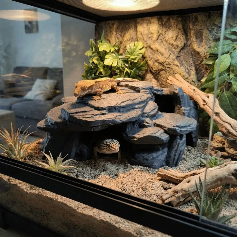 A realistic 3D printed fish tank rockery ornament featuring dark rocks, moss, and greenery.