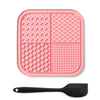 A pink silicone lick mat for pets with suction cups and a black silicone spoon.