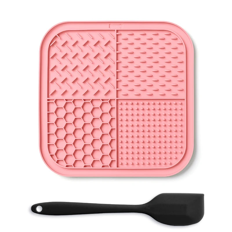 A pink silicone lick mat for pets with suction cups and a black silicone spoon.