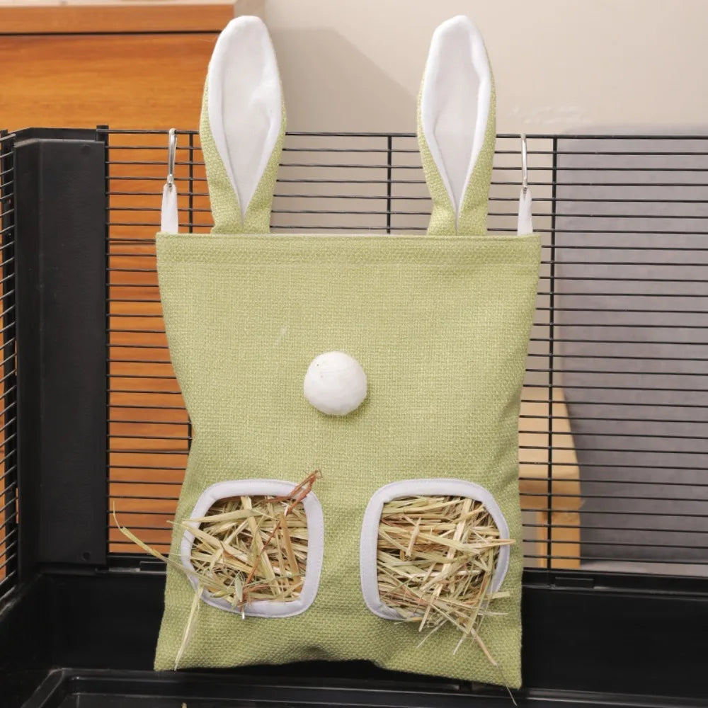 Un sac de foin à toile vert clair avec des formes d'oreilles blanches et de la litière de paille, montré dans un enclos sombr