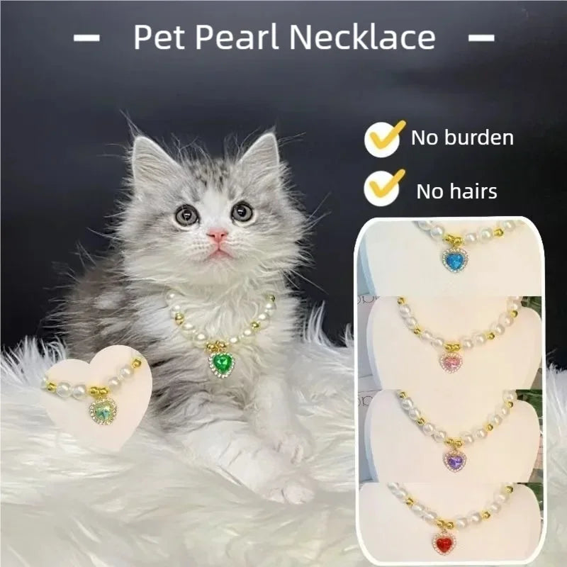 Ein flauschiges graues Kätzchen mit einer zarten Perlenkette mit einem grünen Anhänger.