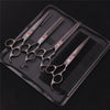 A professional stainless steel pet grooming scissors set with various blades and a comb inside a black leather case.