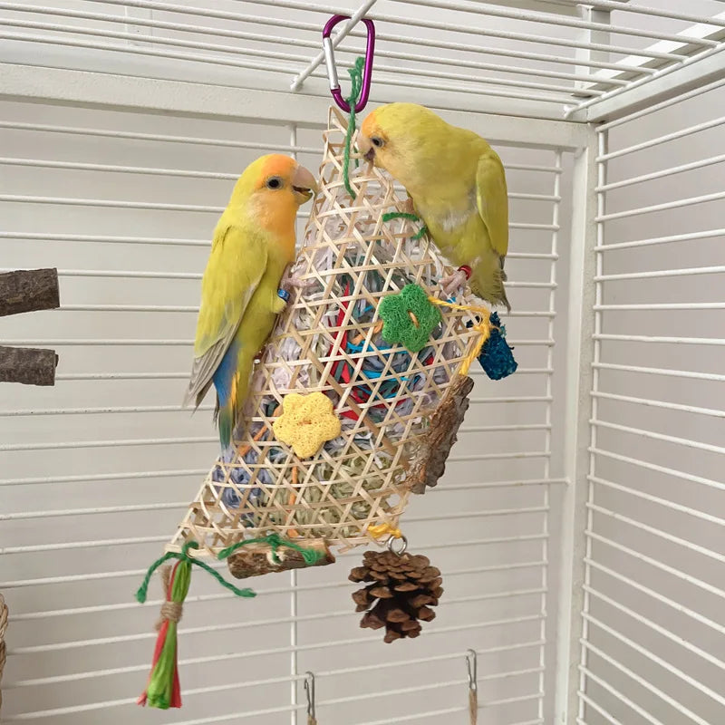 A yellow parrot toy with a bamboo frame filled with colorful shredded paper and natural elements.
