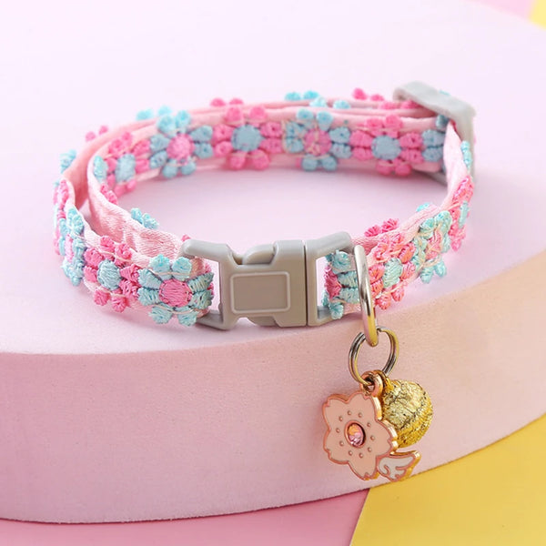A pink and blue crocheted collar with a silver buckle and a gold safety bell for pets