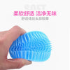 A hand holds a bright blue silicone brush with numerous bristles, used for scalp massage.
