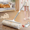 A silver and white retractable lint roller mop with refill rolls is shown on a wooden floor next to a dog and a person.