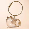 A clear, sculpted cat charm attached to a gold-colored hair storage keychain ring.