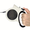 A hand is holding an illuminated retractable dog leash with a white and black body.