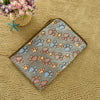 A gray pet bed mat cover featuring a pattern of paw prints in shades of pink, orange, and blue, resting on a yellow textured 
