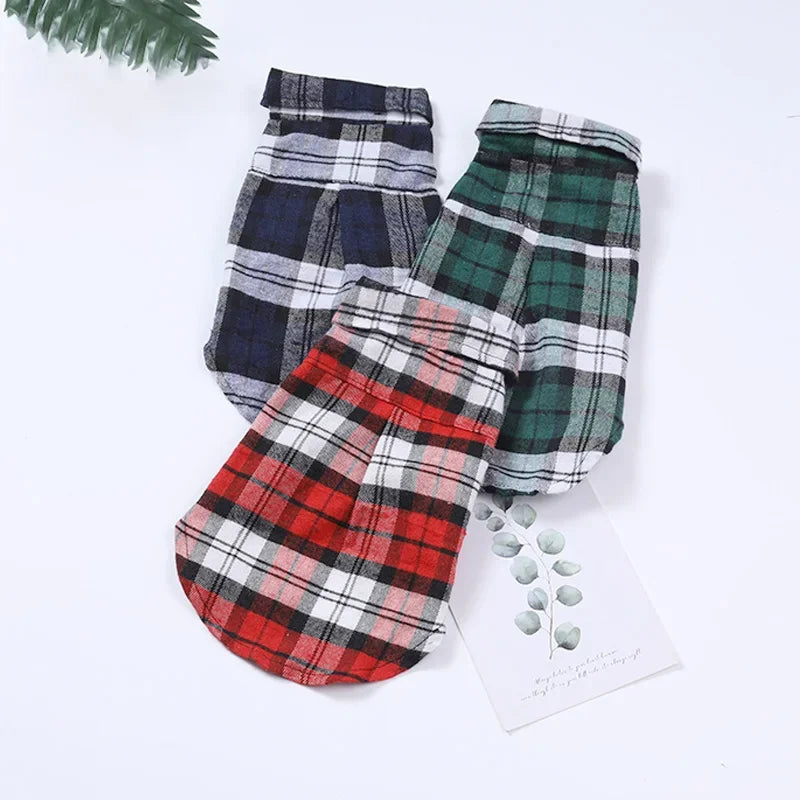 Trois gilets de vêtements pour chiens à carreaux rouges, verts et bleus sur fond blanc.