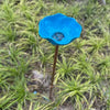 A bright blue stainless steel bird feeder with a small, textured bowl is shown planted in green grass.