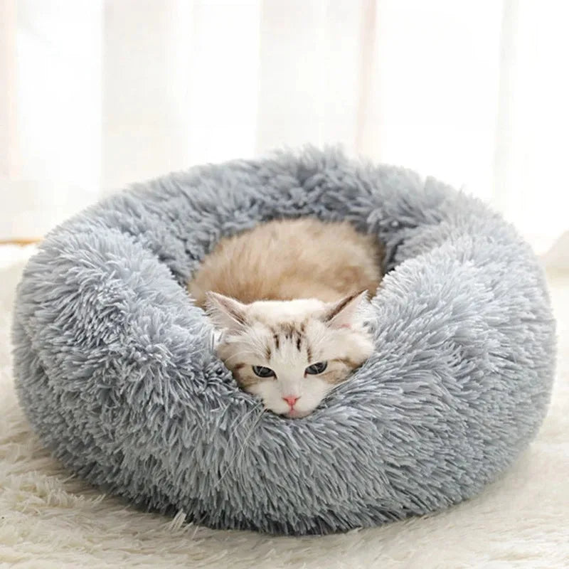 A fluffy gray round bed filled with faux fur, featuring a small tabby cat nestled inside.