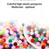 Verschiedene bunte, hochelastische Plüschbälle und Pompons sind auf einer weißen Fläche verstreut.