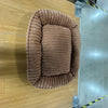 Un lit pour animaux rond et brun en peluche, conçu pour chiens et chats, monté sur une surface en bois clair.