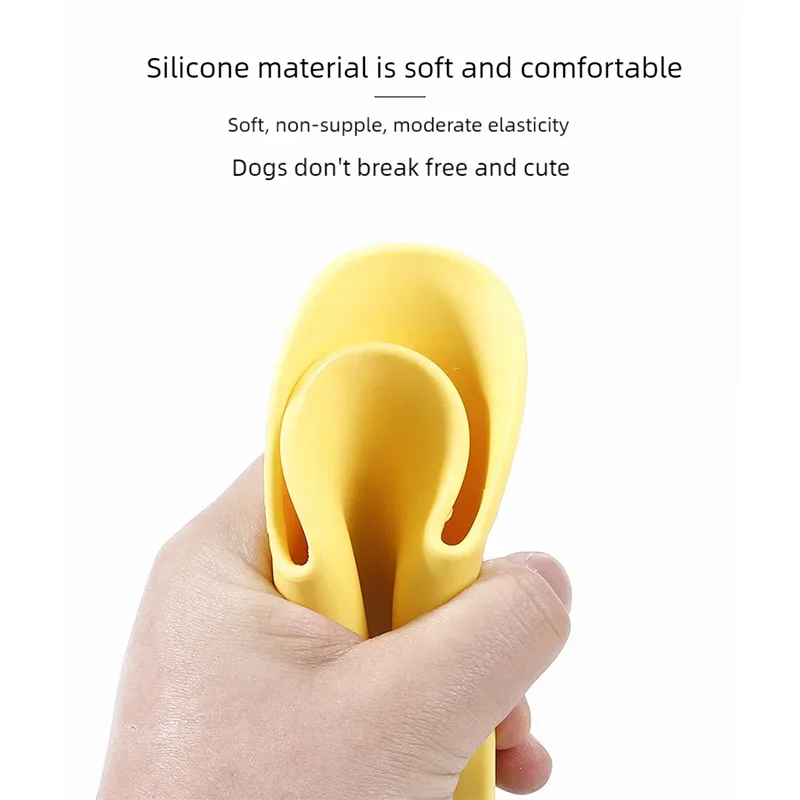 A hand is holding a yellow silicone dog muzzle designed for small to medium dogs.