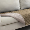 A beige and white reversible waterproof pet mat with a quilted texture is shown on a white sofa cushion.