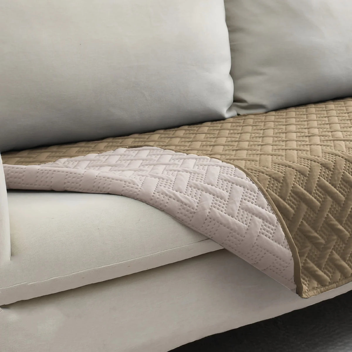A beige and white reversible waterproof pet mat with a quilted texture is shown on a white sofa cushion.