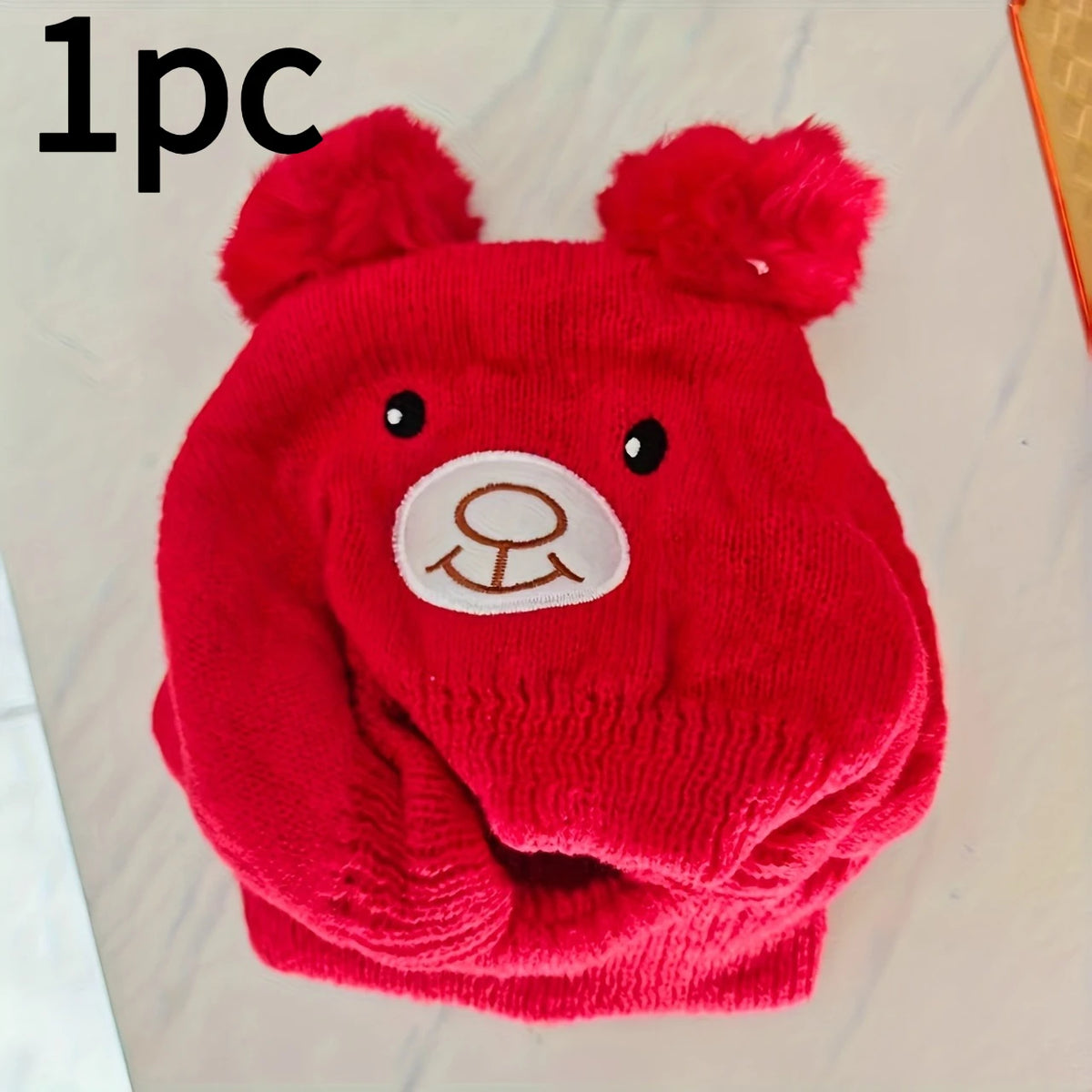 A bright red knitted hat and scarf set featuring bear ears.