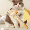 A fluffy gray and white kitten is sitting next to a yellow pet brush with massage pins.