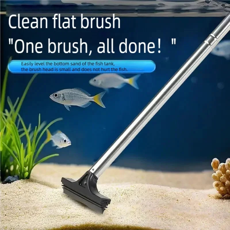 A silver telescopic flat brush is shown cleaning sand from the bottom of an aquarium tank.