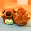 An orange capybara plush hoodie doll with wings resting on a blue fabric surface.