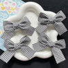 Black and white plaid fabric bow hair clips for girls displayed on a white plate.