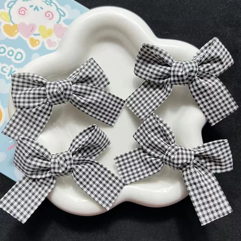 Black and white plaid fabric bow hair clips for girls displayed on a white plate.
