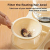 A hand is filtering floating hair from a bowl of water using a 2-in-1 automatic pet feeder.