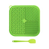 A bright green silicone licking mat for pets with suction cups and a matching spoon.