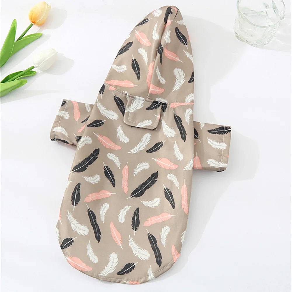 A beige cartoon printed dog raincoat featuring black and pink feather patterns, displayed on a white surface.