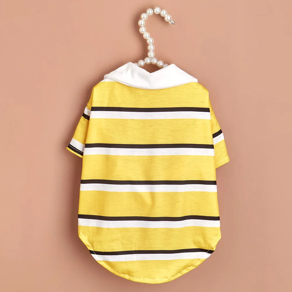 A yellow and white striped polo shirt for a small dog is displayed on a hanger.