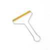 A manual lint remover brush with a gold-colored handle and silver metal frame.