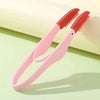 A pink and orange comb tool for pet tear stain removal resting on a light green surface.