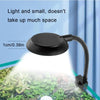 A black USB clip-on LED aquarium light illuminates aquatic plants on a surface.