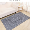 Gray pet pee pads are laid out on a light wooden floor in front of a white sofa.