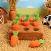 An interactive snuffle mat for pets featuring orange carrot-shaped toys and greenery set against a straw background.