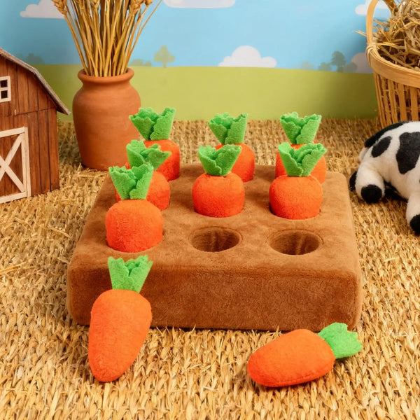 An interactive snuffle mat for pets featuring orange carrot-shaped toys and greenery set against a straw background.