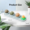 A row of edible catnip licking balls in various sizes displayed on a white marble surface.