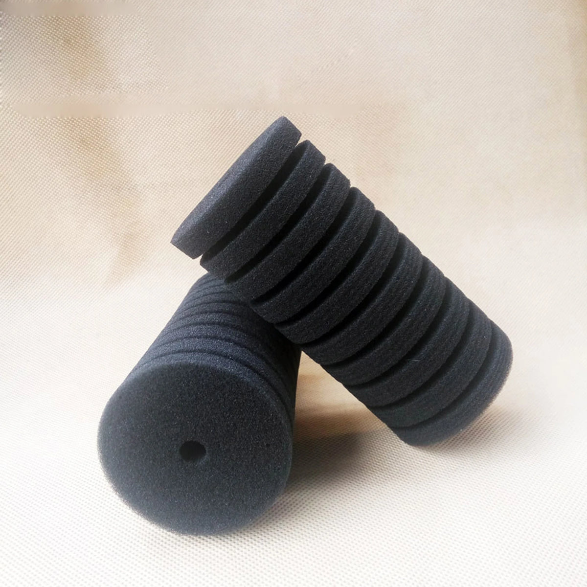 A stack of black biological aquarium sponge filters, showing their ribbed texture and cylindrical shape.