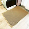 A beige, double-layer cat litter mat with a non-slip base placed on a light wooden floor.