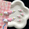 Pink heart-shaped pet hair clips for dogs and cats displayed on a white ceramic dish with pink patterned paper.