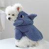 A fluffy white dog wearing a blue fleece pet overalls for dogs and cats.