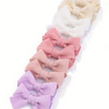 Collection de nœuds pour cheveux en ruban tricotés rose et beige, présentés en rangée.