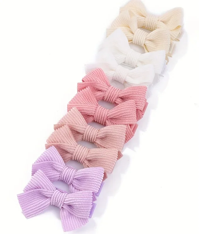 Collection de nœuds pour cheveux en ruban tricotés rose et beige, présentés en rangée.