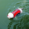 A white dog wearing a red and white life vest swims in green water.