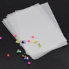 A stack of clear plastic sheets and various colored beads are shown with tweezers.