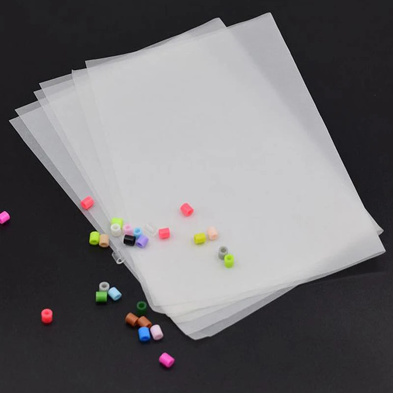 A stack of clear plastic sheets and various colored beads are shown with tweezers.