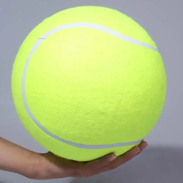 A bright neon yellow tennis ball with white seam lines is held in a person's hand.